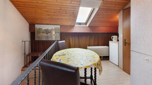 A dining area with a table covered in a lemon pattern, a wooden ceiling, a radiator, and a window. - Guest Room Koch with Panoramic View, Private Terrace and Wi-Fi (Bad Säckingen)