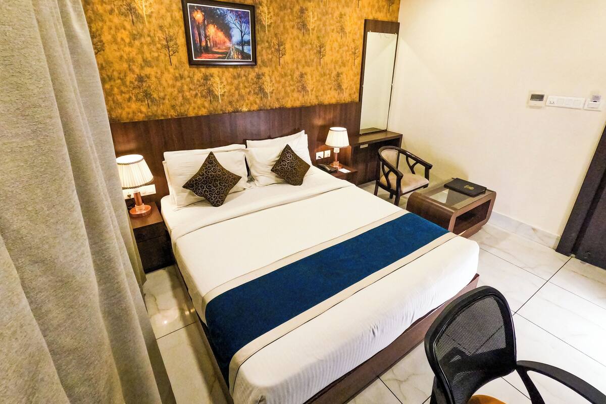 Une chambre d’hôtel avec un lit, un bureau, une chaise, une lampe et un tableau au mur.