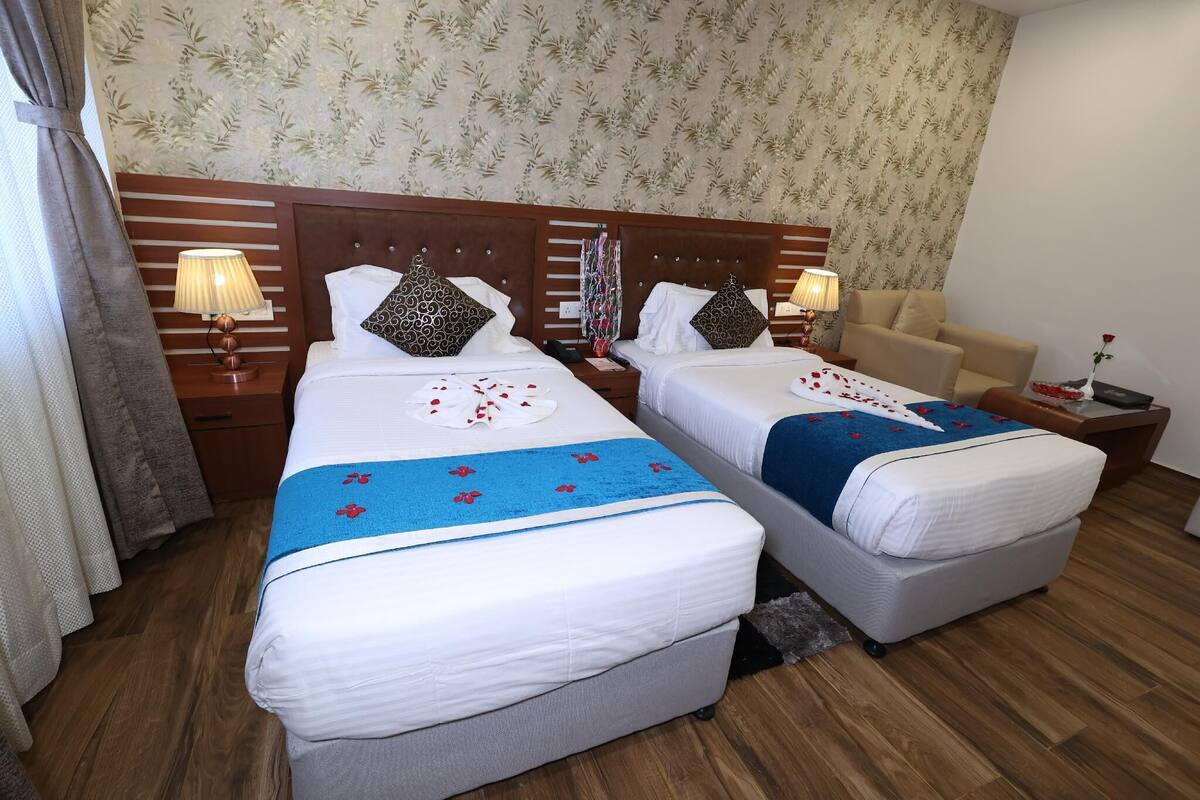 Une chambre d’hôtel avec deux lits, une tête de lit en bois, un canapé et une petite table avec une lampe.