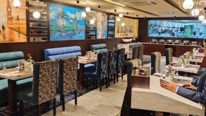 Un restaurante con cabinas y mesas, una barra y una pantalla grande que muestra una escena de cocina.
