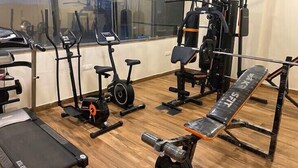 Un gimnasio con máquinas de cardio, equipo de levantamiento de pesas y una banca.