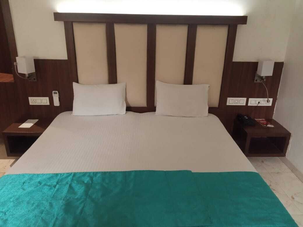A hotel room with a large bed, two bedside tables, and a headboard with vertical panels.