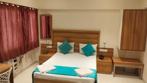 Ein Hotelzimmer mit einem hölzernen Bett, zwei Nachttischen, einem Schreibtisch und einem Kleiderschrank.