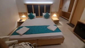 Ein Hotelzimmer mit einem großen Bett, zwei Nachttischen, einem Kleiderschrank und einem Fernseher.