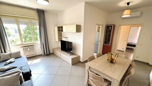 Un salon moderne comprenant un canapé, un téléviseur, une table à manger et des chaises.