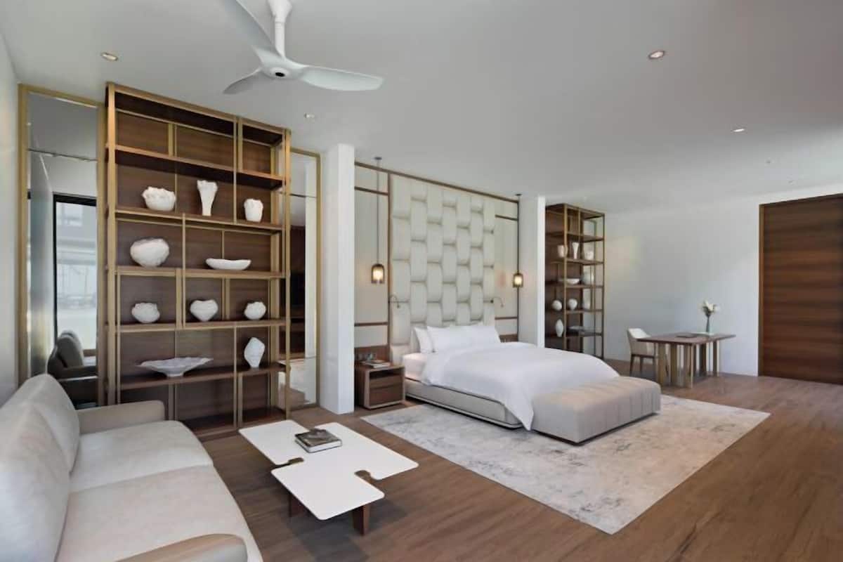 A modern bedroom with a bed, a sofa, a coffee table, and a bookshelf.