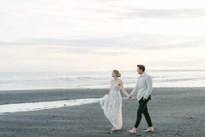 Una pareja caminando en la playa con el océano al fondo.