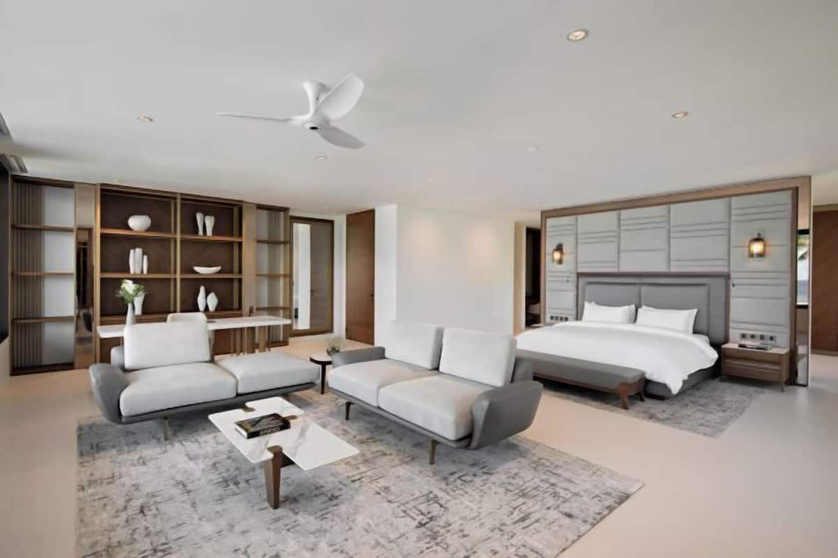 A modern bedroom with a large bed, two sofas, a coffee table, and built-in shelving.