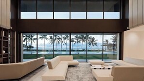 A modern living room with a large window overlooking palm trees and a pool. - Saba Estate Luxury Villa Bali (Bali)