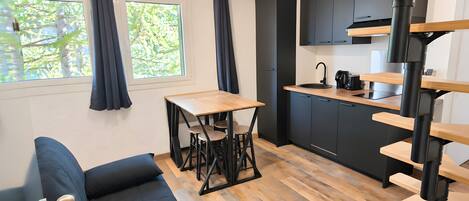 A compact living space with a kitchenette, a dining area, and a sofa.