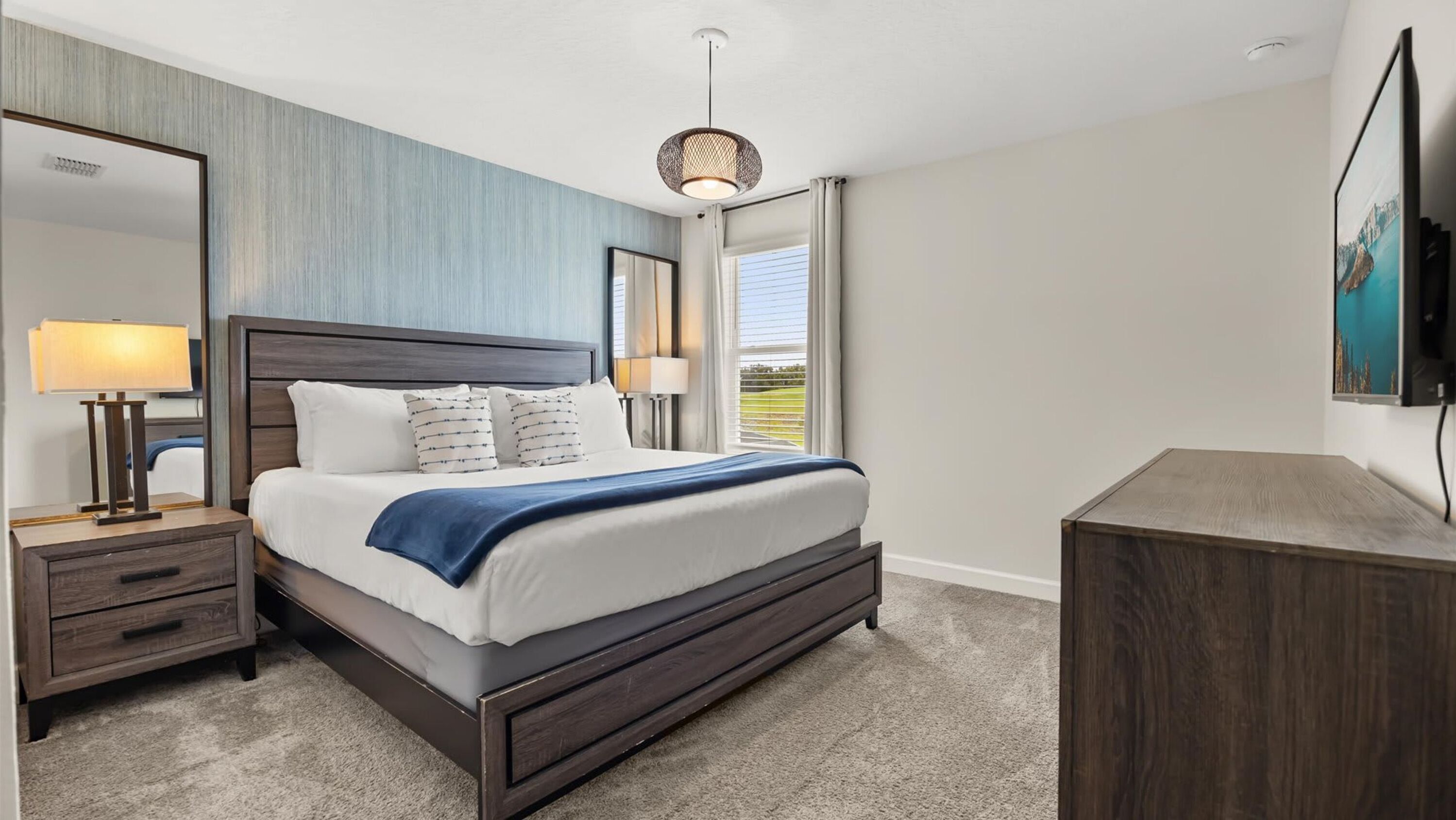A modern hotel room with a large bed, bedside tables, a desk, and a TV.