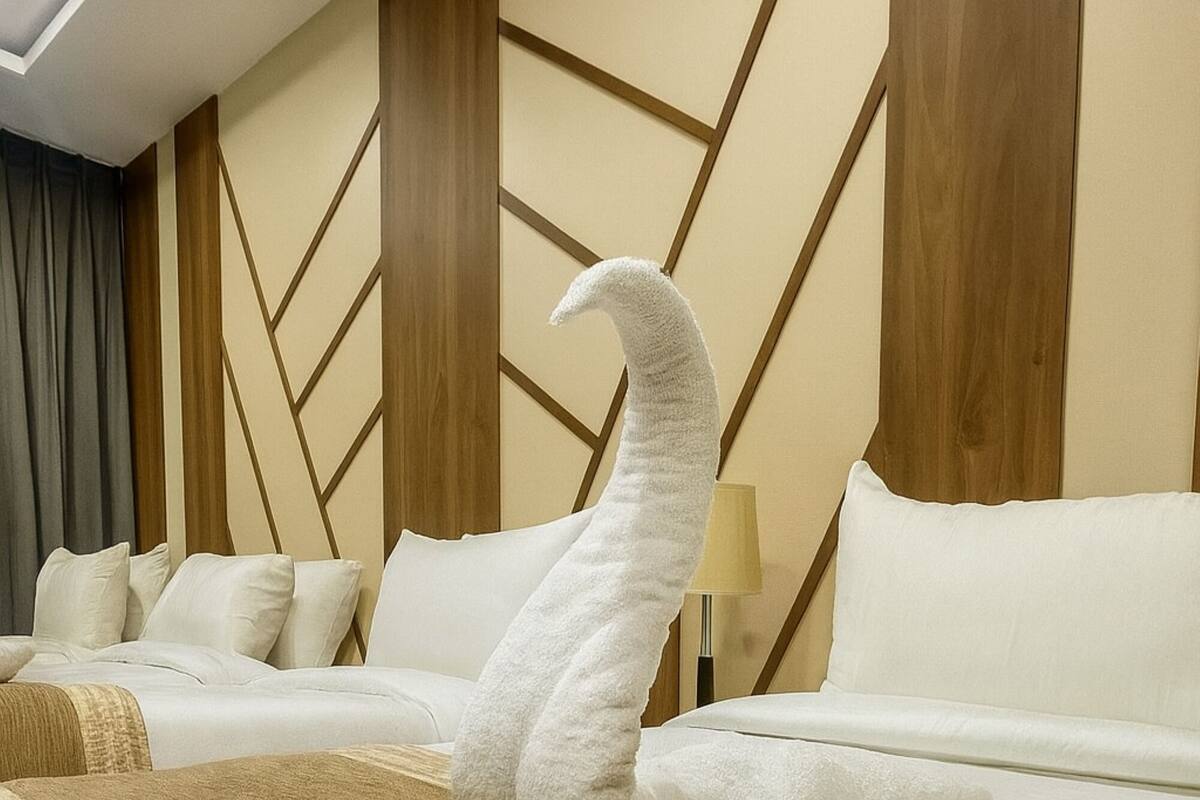 Ein Hotelzimmer mit einem großen Bett, einem Holz-Kopfteil und einem geometrischen Wandmuster.
