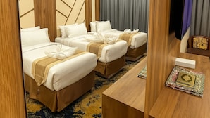 A hotel room with three beds, a wooden desk, and a television. - Moro Alalameyah Hotel Makkah (Makkah)