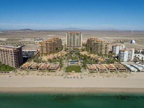 A coastal resort with multiple high-rise buildings, a central pool, and a beach area.