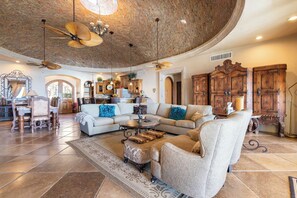 A spacious living room with a curved ceiling, a large sectional sofa, a coffee table, and a fireplace.