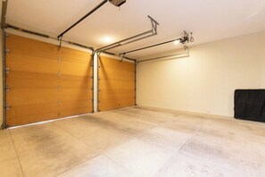 A garage with a wooden door, tiled floor, and a black object on the right.