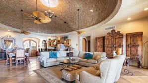 Un salon spacieux doté d’un plafond incurvé, d’un grand canapé d’angle, d’une table basse et d’une cheminée.