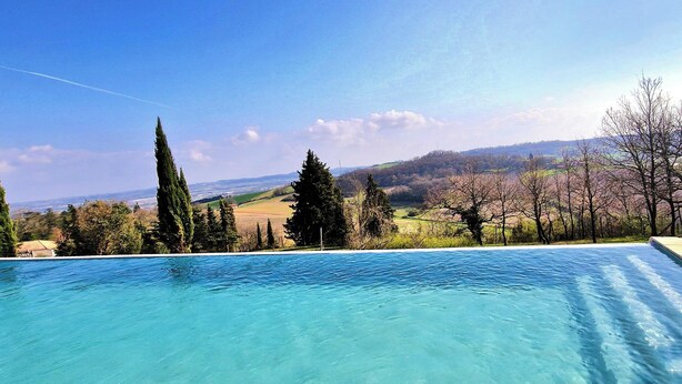 Ein Schwimmbecken mit freiem Blick auf eine hügelige Landschaft im Hintergrund.