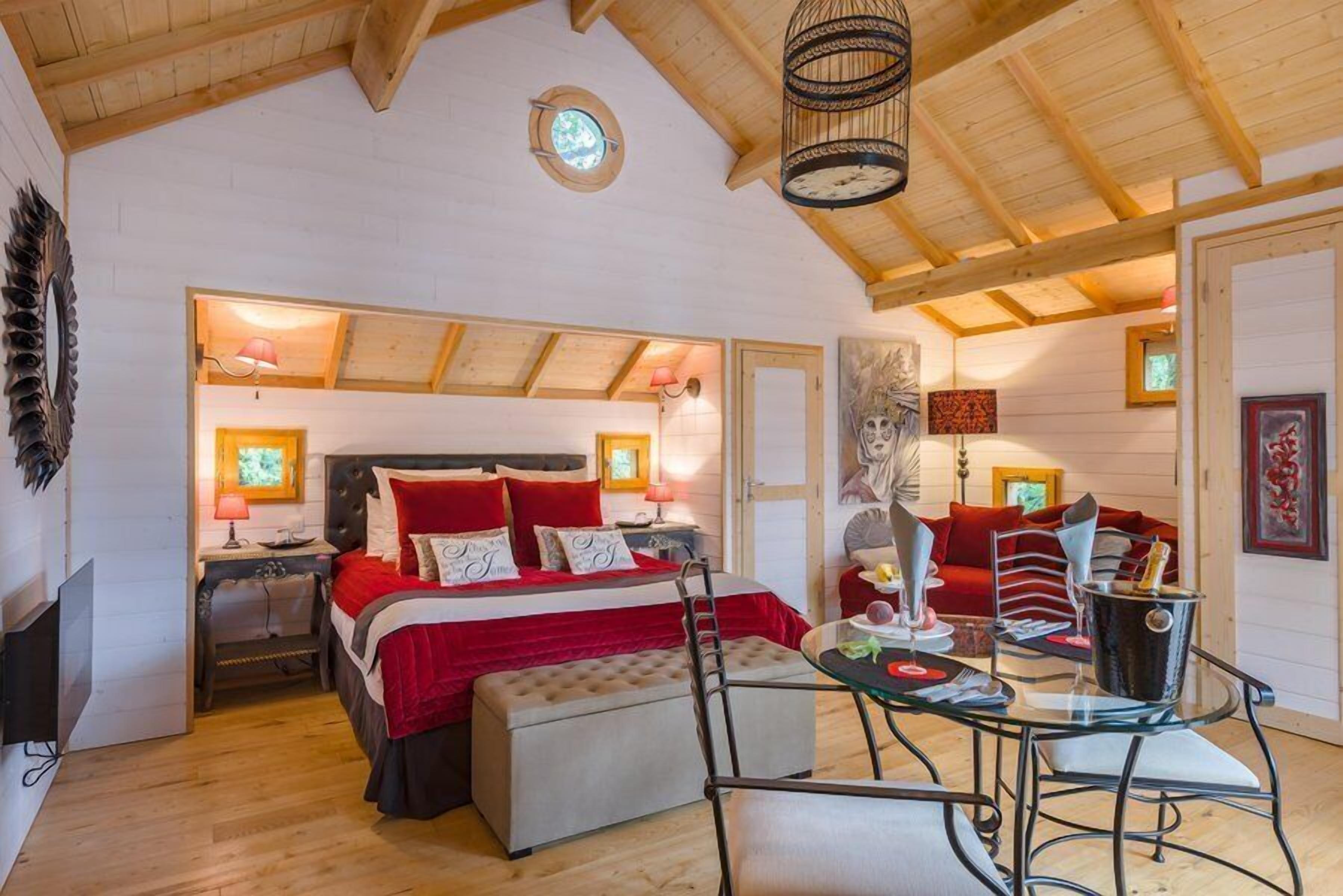 Une chambre confortable avec un grand lit, une petite table et une chaise. Il y a une fenêtre donnant sur l’extérieur.