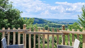 Eine Holzterrasse mit Korbmöbeln und Blick ins Grüne.