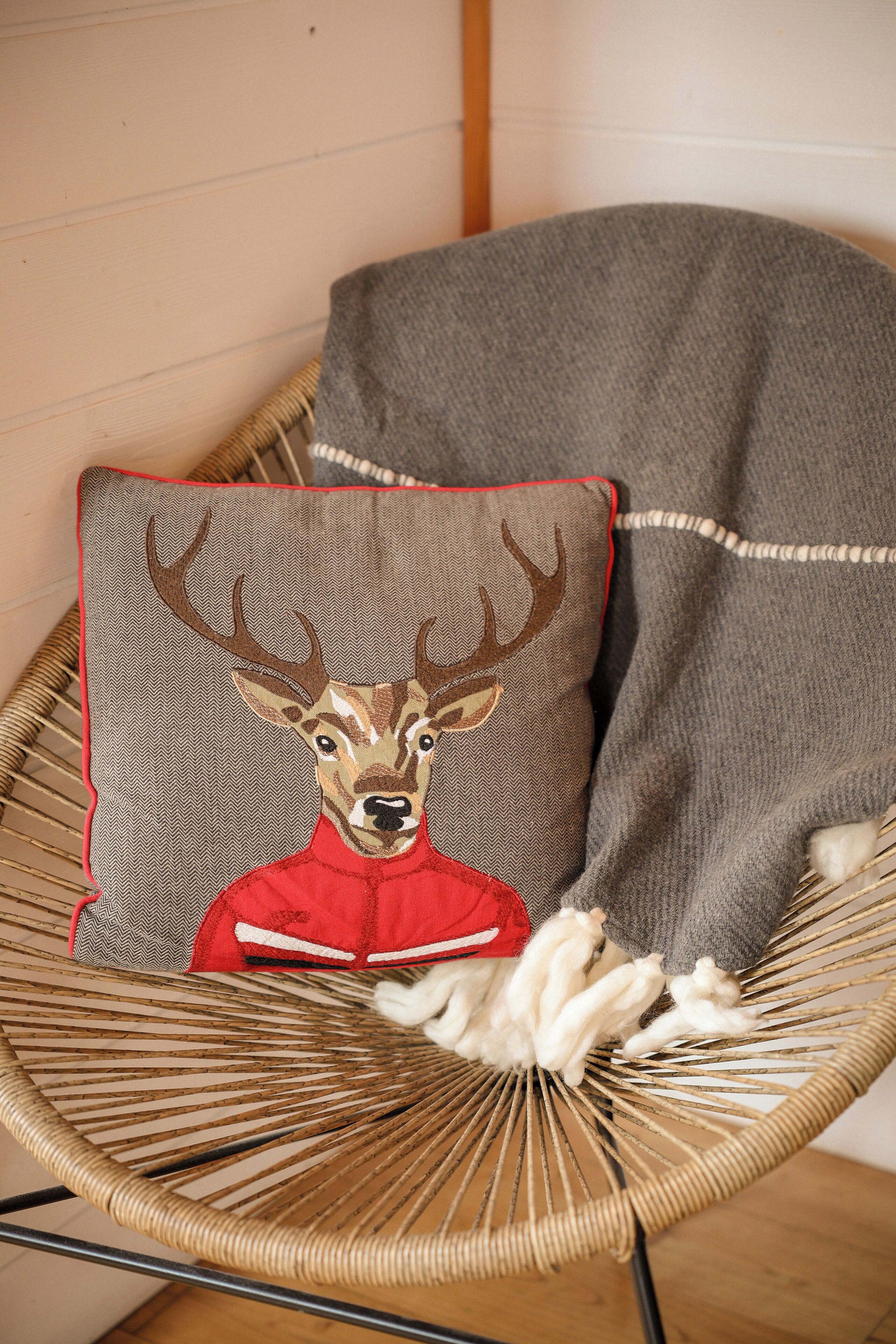 A wicker chair with a cushion featuring a deer design.