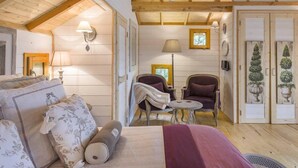 Ein gemütliches Zimmer mit einem Bett, zwei Stühlen, einem kleinen Tisch und einer Lampe.