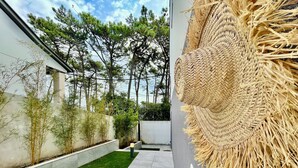 A modern outdoor area with a paved walkway, green grass, and a wall with a woven texture.