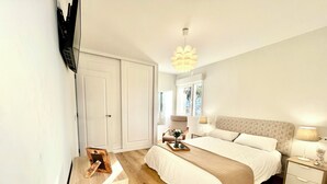 A bedroom with a bed, bedside tables, a chair, a desk, and a wardrobe.