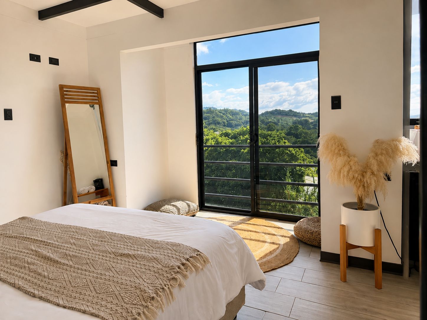 Ein Schlafzimmer mit einem großen Bett, einem Spiegel, Blick ins Grüne und modernem Design.