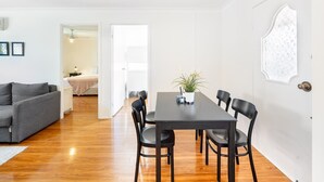 Un salon moderne comprenant un coin repas, un plancher en bois et une porte blanche agrémentée d’un panneau de verre décoratif.