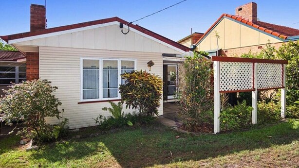 A single-story house with a front door, a garage, and a small garden area with various plants.