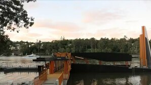A waterfront area with a bridge, a boat dock, and a pedestrian walkway.