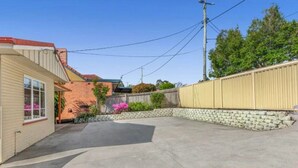 A residential backyard with a paved area, a brick wall, and a wooden fence.