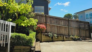 A residential area with a wooden fence, a house with a window, and a clear blue sky. - LILYPAD 4-bedroom Urban Retreat Auckland (Auckland)