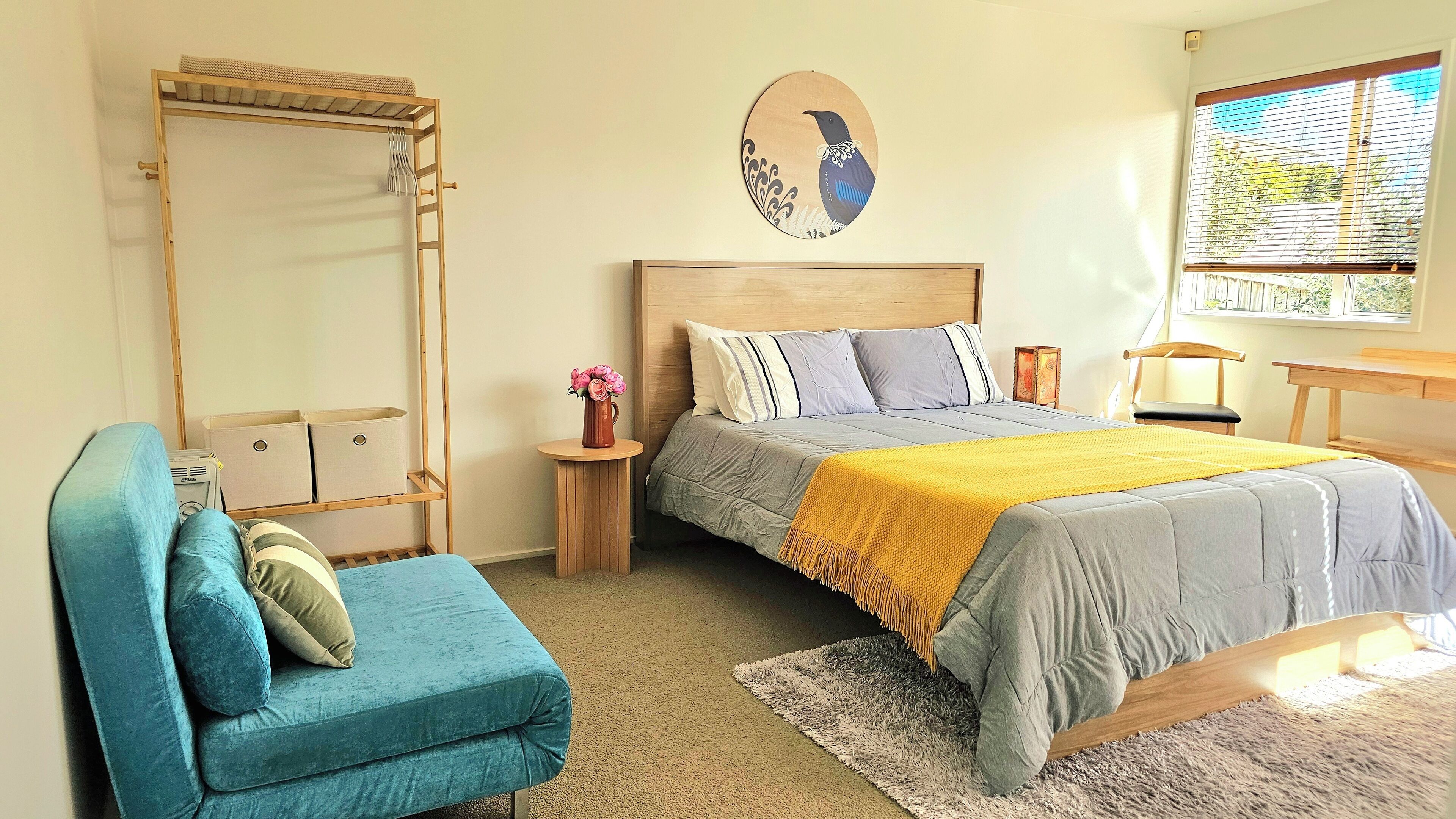 Ein Schlafzimmer mit Bett, Stuhl, Nachttisch, Spiegel und Wandbild.