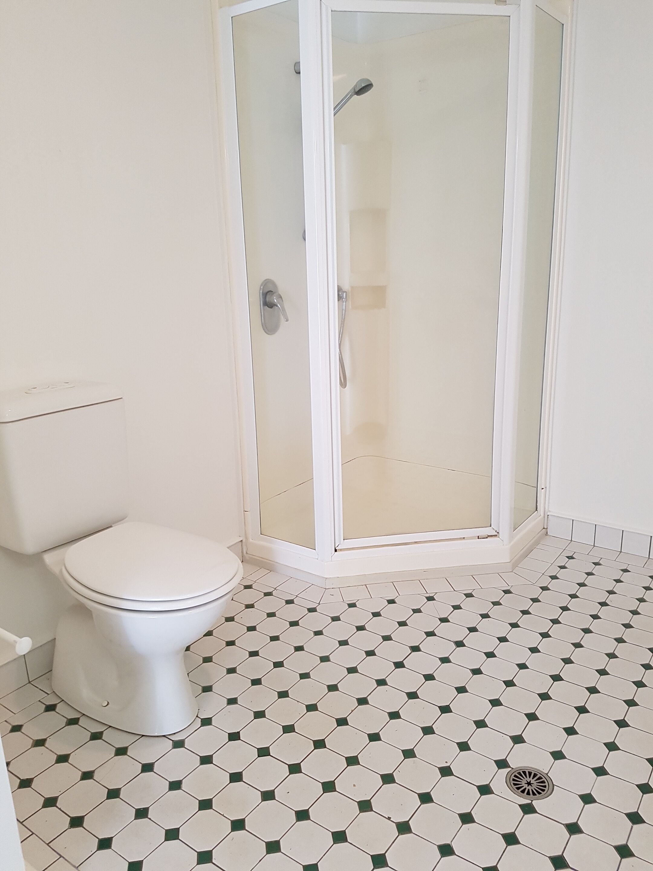 Un bagno con il water, cabina doccia e pavimento piastrellato.