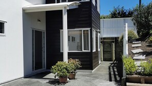 A modern two-story house with a balcony, potted plants, and a clear sky. - LILYPAD 4-bedroom Urban Retreat Auckland (Auckland)