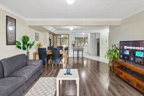 Ein modernes Wohnzimmer mit einem grauen Sofa, einem kleinen weißen Couchtisch und einem Fernseher auf einem Holzschrank.
