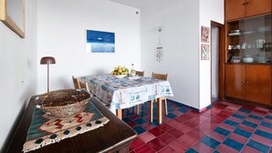 A dining area with a table set for four, a decorative bowl, a wall-mounted picture, and a cabinet with glass doors. - Sea Scent - My Rental Homes (San Montano)
