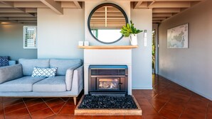 A modern living room with a fireplace, a sofa, a coffee table, and a potted plant.