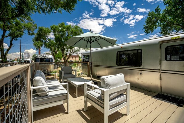 Una terraza con mobiliario exterior, un espacio cubierto y una caravana.