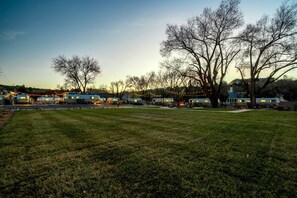 A campground with RVs parked in rows, trees, and a grassy field.