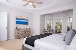 Un dormitorio con cama, cómoda, televisor y ventilador de techo.