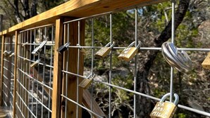 A wooden bridge with metal railings and multiple padlocks.