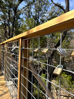 A wooden bridge with metal railings and multiple padlocks.