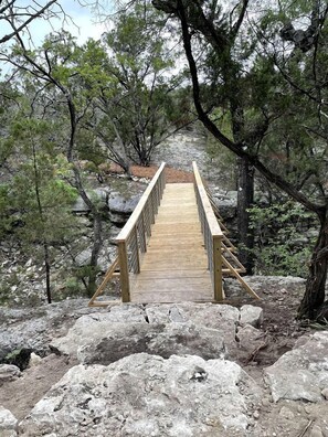 Un pont de fusta en una zona boscosa amb terreny rocos.