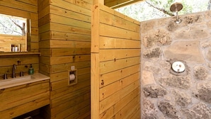 Une cabane en bois avec un mur en pierre, un banc en bois et une petite fenêtre.