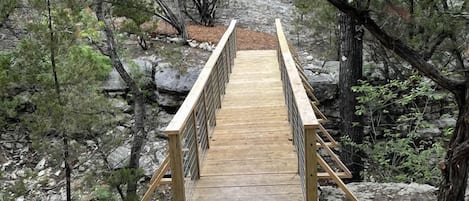 A wooden bridge in a forested area with rocky terrain.
