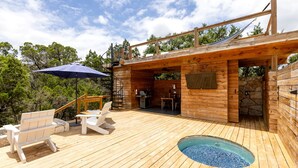 Une terrasse en bois avec un jacuzzi, un espace salon extérieur et un coin barbecue.
