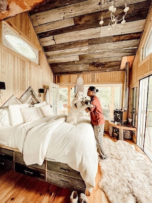 A rustic bedroom with a wooden bed, a large window, and a fireplace. - Stunning Pet-Friendly Treehouse for Relaxing Glamping Retreats in North Carolina (Cantón)